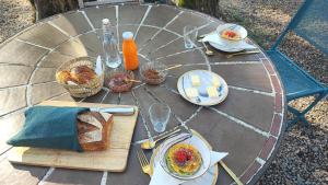 a table with a plate of food and bread on it at Le Mas Mélusine Chambres d hôtes avec piscine en oliveraie à Fayence in Fayence
