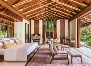 a bedroom with a large bed and a living room at One&Only Reethi Rah in Reethi Rah