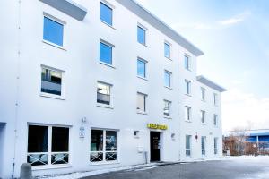 un bâtiment de bureau avec une façade blanche dans l'établissement B&B Hotel München-Putzbrunn, à Putzbrunn