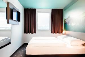 Cette chambre comprend 2 lits et une télévision. dans l'établissement B&B Hotel München-Putzbrunn, à Putzbrunn