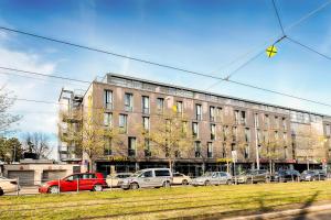 un gran edificio con coches estacionados frente a él en B&B Hotel München-Moosach en Múnich