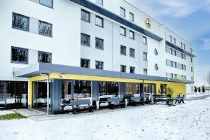 ein Hotelgebäude mit einer Terrasse mit Tischen und Bänken in der Unterkunft B&B HOTEL München-Airport in Hallbergmoos