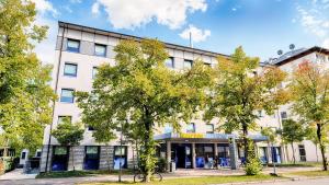 un gran edificio blanco con árboles delante de él en B&B Hotel München-Garching en Garching bei München