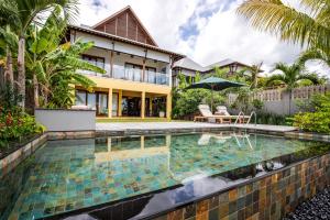 a swimming pool in front of a house at JA Enchanted Waterfront Seychelles in Mahe