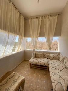 a living room with a couch and a large window at Dar Lily, villa familiale avec piscine et services in Skoura