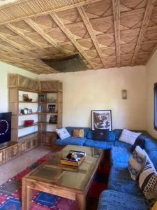 a living room with a blue couch and a table at Dar Lily, villa familiale avec piscine et services in Skoura