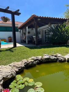 a pond in front of a house with lilies at Cafofos da Zeta, Cozy Pool House in Quinta do Conde