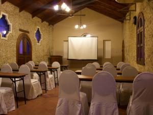 a conference room with tables and chairs and a white screen at Hotel del Patio in Flores