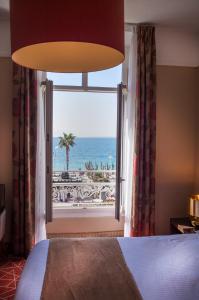 een slaapkamer met een raam met uitzicht op de oceaan bij Excelsior in Saint-Raphaël