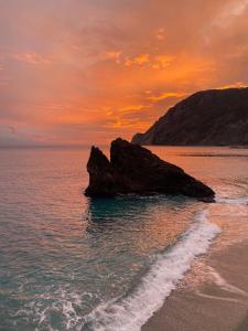a beach with a rock in the water at sunset at Affittacamere Benvenuti Monterosso in Monterosso al Mare