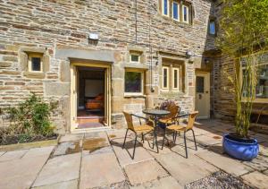 a patio with a table and chairs in front of a building at TLasses Cottage in Kildwick