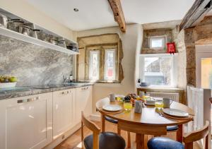 uma cozinha com uma mesa de madeira, uma mesa e cadeiras em TLasses Cottage em Kildwick