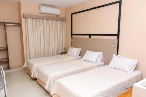 two beds in a hotel room with white sheets at Arrey Fórmula Hotel - Teresina in Teresina