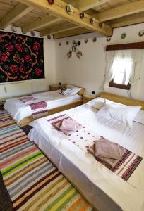 two twin beds in a room with a rug at Căsuța lui Gogu in Borsa