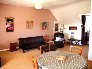 sala de estar con sofá, mesa y sillas en Les Gîtes du Couvent Alternatif, en Camlez