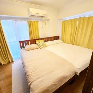 2 Betten in einem Schlafzimmer mit gelben Vorhängen in der Unterkunft 歌舞伎町704 in Tokio