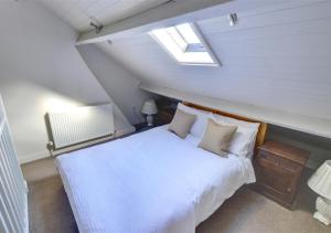 a bedroom with a white bed in a attic at Thornwick Cottage in Staithes