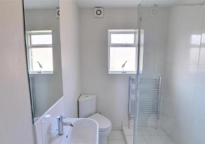 a white bathroom with a toilet and a shower at Thornwick Cottage in Staithes