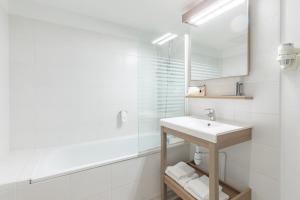 La salle de bains blanche est pourvue d'un lavabo et d'un miroir. dans l'établissement Appart'City Classic Valence, à Valence