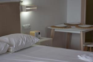 a bed with a pillow and a table with plates on it at Alexandros Beachfront Apartments near Petalidi with Private Sunbeds & Sea View in Kalamaki Messinia