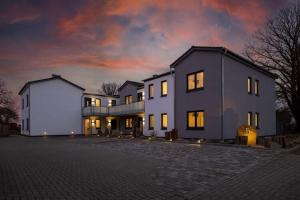 a large white house with a sunset in the background at Exclusives Appartement auf Fehmarn in Petersdorf auf Fehmarn