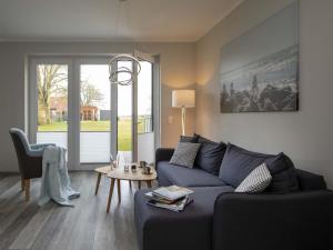 a living room with a blue couch and a table at Exclusives Appartement auf Fehmarn in Petersdorf auf Fehmarn