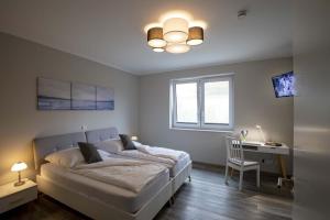 a bedroom with a bed and a desk and a chair at Exclusives Appartement auf Fehmarn in Petersdorf auf Fehmarn
