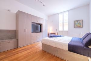 a bedroom with a large bed and a flat screen tv at D'Azeglio & Galluzzi Suites in Bologna