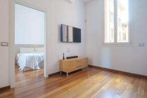 a white room with a tv and a bed at D'Azeglio & Galluzzi Suites in Bologna