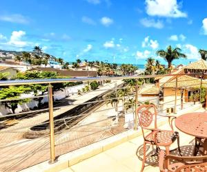 uma varanda com mesas e cadeiras e vista para o oceano em Hotel Rosa da Ilha - Pertinho do Mar com piscina no Guarujá