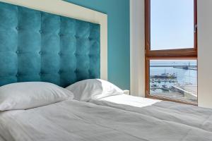un lit avec une tête de lit bleue et une fenêtre dans l'établissement Sea Towers, à Gdynia