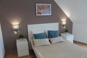 een slaapkamer met een bed met blauwe kussens en 2 nachtkastjes bij El Ático de la Estación in Oviedo