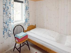 a bedroom with a bed and a chair and a window at Holiday home Laukvik III in Laukvik