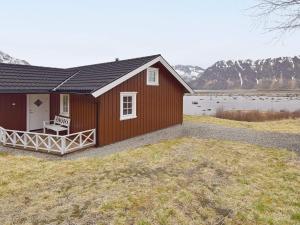 un edificio rojo con un banco a un lado de un lago en Holiday home Laukvik III, en Laukvik