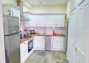 uma cozinha com armários brancos e um frigorífico de aço inoxidável em The Secret Garden em Whitby