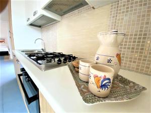 un bancone della cucina con due tazze e una brocca su uno scaffale di Suite Petrelli a Torre dell'Orso