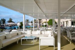 eine Terrasse mit weißen Sofas, Tischen und Stühlen in der Unterkunft Grand Teguise Playa in Costa Teguise