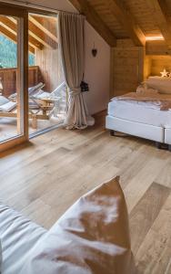 a bedroom with two beds and a large window at Chalet Le Coccole in Sappada