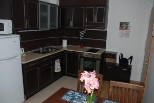 une cuisine avec des armoires noires et un vase de fleurs sur une table dans l'établissement Marina Hotel Apartaments, à Pomorie