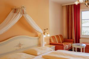 a bedroom with a bed and a chair and a window at Schlössl Hotel Kindl in Bad Gleichenberg