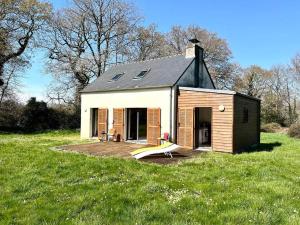 une petite maison avec une terrasse dans un champ dans l'établissement Maison de charme dans la nature, à Clohars-Fouesnant