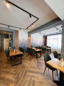 un restaurante con mesas de madera y sillas verdes en Hotel Muntele Mic en Borlova