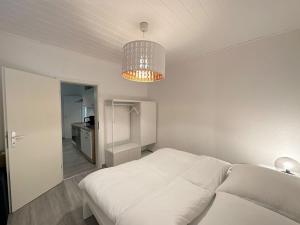 um quarto com uma cama branca e um lustre em Möblierte EG- Wohnung zentral in Herne mit Parkplatz,WLAN und Netflix em Herne