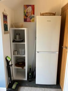 um frigorífico branco numa cozinha ao lado de uma prateleira em The parlour em Bodmin