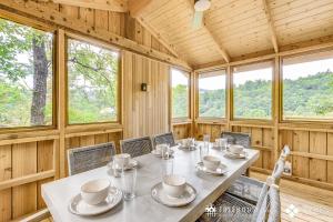 a dining room with a table and chairs and windows at The Blackjack Oak in Treehouse Grove at Norton Creek in Gatlinburg