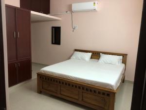 een slaapkamer met een bed met witte lakens en een kast bij Tirumala Elite Homestay (near Railway station & Bustand) in Tirupati