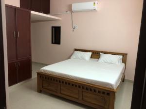 a bedroom with a bed with white sheets and a cabinet at Tirumala Elite Homestay (near Railway station & Bustand) in Tirupati