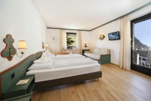 a bedroom with two beds and a living room at Parkhotel Tirolerhof in Lagundo