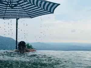 uma pessoa numa piscina com um guarda-chuva em SANKARA GARDEN 