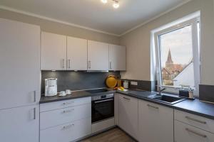 une cuisine avec des placards blancs et une grande fenêtre dans l'établissement Exclusive apartment on Fehmarn, à Petersdorf auf Fehmarn